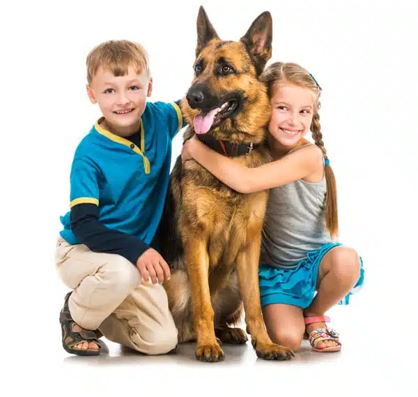 Young boy and girl kneeling down and holding their dog while smiling